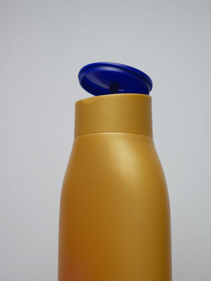 Services Close-up of a gold plastic bottle with a blue flip cap against a neutral background.